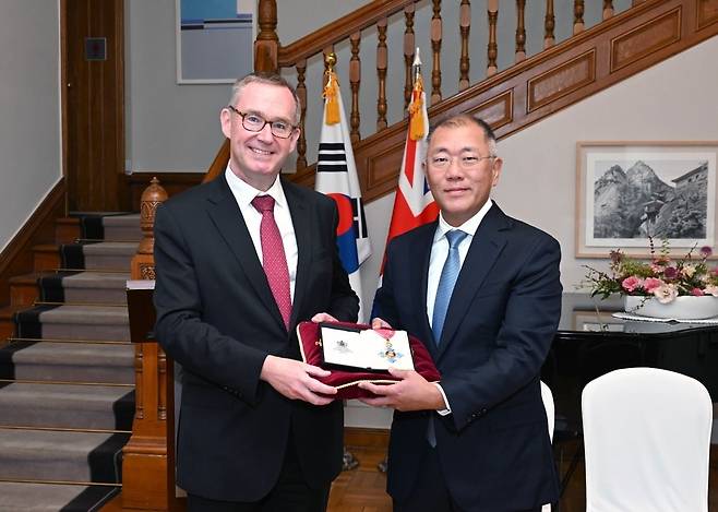 정의선(오른쪽) 현대자동차그룹 회장이 14일 주한 영국 대사관에서 열린 대영제국훈장 수훈식에서 영국 찰스 3세 국왕이 수여하는 대영제국 지휘관 훈장(Honorary Commander of the Most Excellent Order of the British Empire, CBE)을 수훈했다. 찰스 3세 국왕 즉위 이후 한국인으로는 처음이다. 정 회장이 대영제국 지휘관 훈장을 들고 콜린 크룩스 주한 영국 대사와 기념촬영 하고 있다. 사진=현대차그룹 제공.