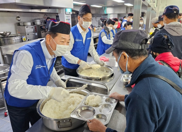 한종희(왼쪽) 삼성전자 부회장이 일상 속 나눔을 실천하기 위해 지난 6일 경기 성남시 사회복지기관 ‘안나의 집’에서 노숙인에게 배식을 하고 있다.  삼성전자 제공