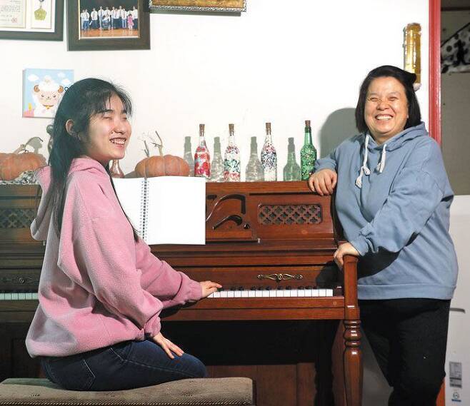 18일 박정순씨(오른쪽)가 경기도 포천 자택에서 피아노 앞에 앉은 딸 유예은씨와 함께 활짝 웃고 있다. 모녀는 “(예은씨가)대학을 졸업하면 피아노를 통해 지금껏 받았던 것을 세상에 다시 돌려주면서 살자고 약속했다”고 말했다. /장련성 기자