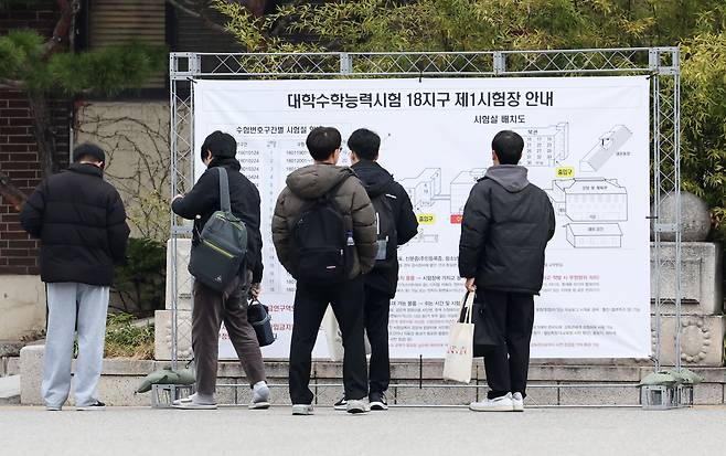 Test-takers for this year’s Suneung, or South Korea’s college entrance exam, look at the seating chart of the exam room at Whimoon High School in Gangnam, southern Seoul, Thursday. (Newsis)