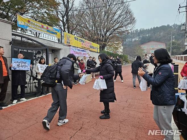 [보은=뉴시스] 안성수 기자 = 2024학년도 대학수학능력시험일인 16일 충북 보은군 보은고등학교 앞에서 학부모가 수험생에게 격려품을 나눠주고 있다. 2023.11.16. hugahn@newsis.com