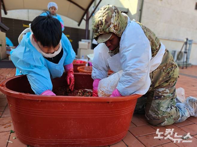 길위의교회 야학에 다니는 어린이(왼쪽)와 주한미군 병사(오른쪽)이 함께 김치소를 만들고 있다.