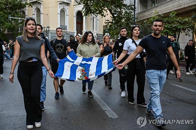 그리스 반독재 학생 봉기 50주년 (아테네 AFP=연합뉴스) 17일(현지시간) 그리스 수도 아테네에서 1973년 학생 봉기 50주년을 기념하는 시위가 벌어졌다. 학생들이 피로 얼룩진 그리스 국기를 들고 행진하고 있다. 2023.11.17 photo@yna.co.kr