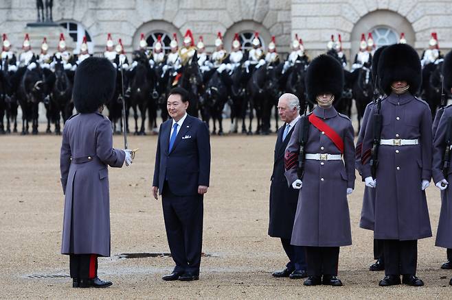 영국을 국빈 방문한 윤석열 대통령이 21일(현지시간) 런던 호스가즈 광장에서 열린 공식환영식에서 찰스 3세 영국 국왕과 왕실 근위대를 사열하고 있다. [연합]