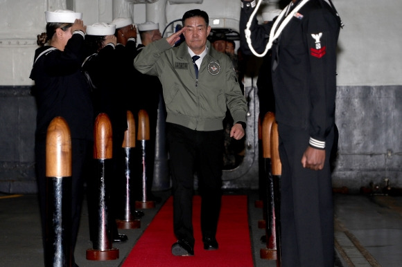 칼빈슨함 승함하는 신원식 장관 - 신원식 국방부 장관이 22일 부산 남구 해군작전사령부 부산작전기지에 입항한 미국 제1항모강습단의 칼빈슨함을 방문해 현문에 도열 중인 칼빈슨함 장병들의 경례를 받으며 함정에 승함하고 있다. 2023.11.22 국방부 제공