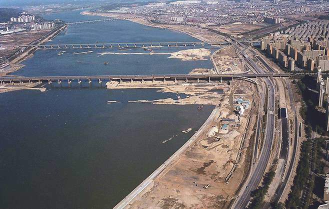 1986년 잠실지구 공사 장면. 잠실대교, 잠실철교, 천호대교가 차례로 보인다. 잠실대교 하단에는 잠실 수중보가 건설되고 있다. 1986년 1월 24일 촬영. - 사진 서울역사박물관.