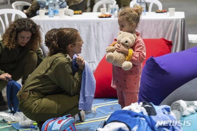 [하체림=AP/뉴시스] 이스라엘 총리실이 제공한 사진에 26일(현지시각) 하체림의 이스라엘 공군기지에서 군인들이 가자지구에서 풀려나 이곳에 도착한 이스라엘 소녀 야헬 쇼함(3)을 돌봐주고 있다. 2023.11.27.