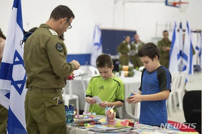 [하체림=AP/뉴시스] 이스라엘 총리실이 제공한 사진에 26일(현지시각) 하체림의 이스라엘 공군기지에서 군인들이 가자지구에서 풀려나 이곳에 도착한 이스라엘 형제와 놀아주고 있다. 2023.11.27.