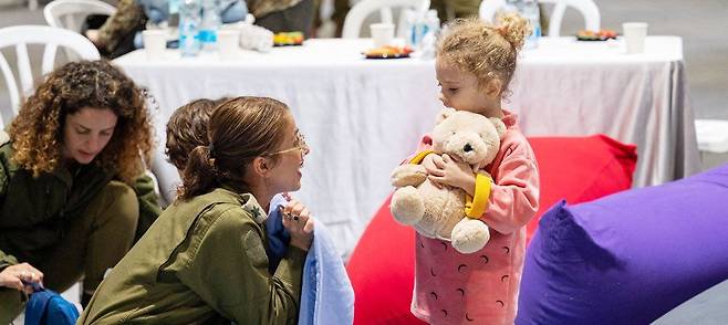 풀려난 어린이의 미소 - 이스라엘과 하마스(이슬람 무장 세력) 휴전 이틀째인 25일(현지 시각) 이스라엘 하체림 공군기지에서 한 이스라엘 군인이 하마스에 납치됐다 풀려난 이스라엘 국적 어린이 야헬 쇼함(3·오른쪽)에게 말을 걸고 있다. 26일까지 하마스는 58명, 이스라엘은 117명의 인질을 각각 풀어줬다. /로이터 연합뉴스