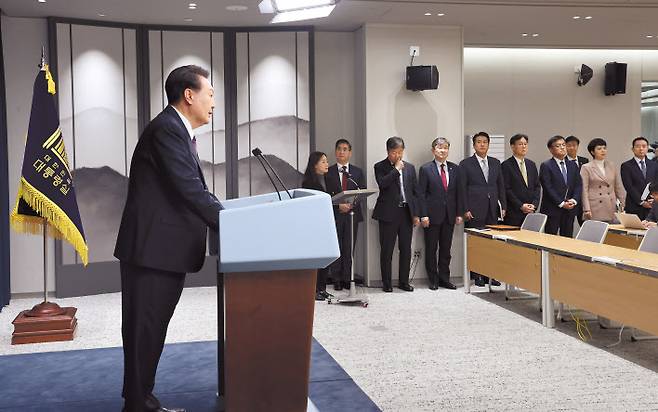 윤석열 대통령이 29일 서울 용산 대통령실 청사에서 대통령실 실장과 수석들이 배석한 가운데 2030 엑스포 부산 유치 실패와 관련한 대국민 담화를 하고 있다. 오른쪽부터 이도운 대변인, 김은혜 홍보수석, 최상목 경제수석, 이관섭 국정기획수석, 김태효 국가안보실 1차장, 조태용 국가안보실장, 김대기 비서실장, 김용현 경호처장, 최지현 부대변인이다. 윤 대통령은 대통령실을 3실 6수석 체제로 개편하고, 참모진을 대거 교체하는 인사도 조만간 단행할 예정이다. [연합]