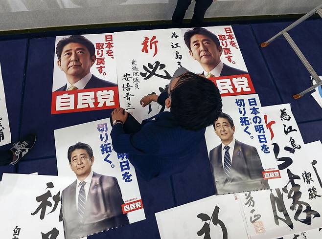 일본 참의원 선거 투표일인 2022년 7월 10일 오후 일본 야마구치현 야마구치시에 있는 에지마 기요시 자민당 후보의 진영에서 관계자가 작업 중인 가운데 아베 신조 전 일본 총리의 사진이 담긴 자민당 홍보물이 놓여 있다. 야마구치현은 2022년 7월 8일 유세 중 총격을 당해 목숨을 잃은 아베 전 총리의 선거구(지역구)였다. 야마구치 교도/연합뉴스