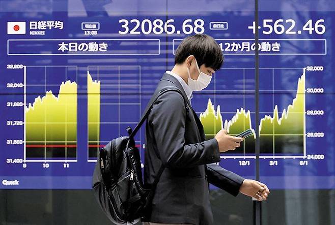 5일 일본 도쿄에서 한 남성이 증시 전광판이 표시된 은행 건물 앞을 지나고 있다. 이날 도쿄증권거래소 닛케이평균은 전 거래일보다 2.2% 오른 3만2217엔에 마감됐다. 이는 1990년 6월 이후 33년 만의 최고치다. /로이터 연합뉴스