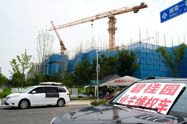 지난달 17일 중국 대형 부동산 업체 비구이위안(컨트리가든)의 베이징 외곽 공사 현장 근처 차량에 '비구이위안 주택 구매자 권리 보호'라고 적힌 팻말이 놓여 있다. 베이징=AP 연합뉴스