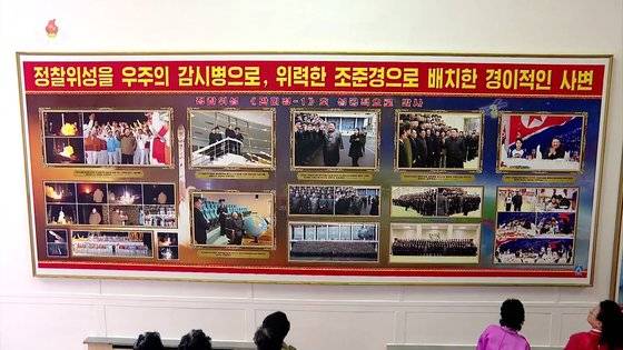 지난 3일 북한 평양체육관에서 열린 어머니대회 참가자들이 정찰위성 관련 사진을 관람하고 있다. 연합
