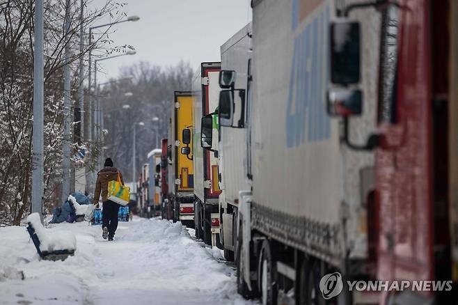 화물 트럭 근처 걸어가는 운전자 [AFP=연합뉴스] 지난 5일(현지시간) 폴란드와 우크라이나 국경 근처에 주차된 차 옆을 한 운전자가 걸어가고 있다. 2023.12.07