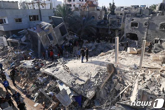 사람들이 형체를 알아보기 힘들 정도로 무너진 건물들 사이에서 실종자를 수색하며 3일(현지시간) 현장을 둘러보고 있다. 2023.12.03 ⓒ AFP=뉴스1 ⓒ News1 정지윤 기자