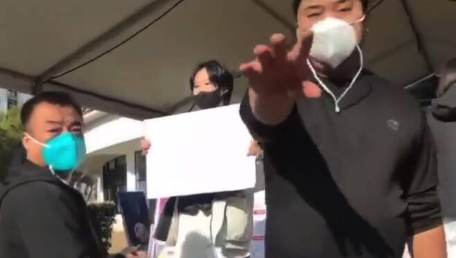 28일 중국 칭화대에서 한 학생이 정부의 코로나 도시 봉쇄에 항의해 백지를 들고 일인 ‘백지(白紙) 시위'를 하는 가운데 공안들이 이 모습을 촬영하는 사람을 제지하고 있다./트위터