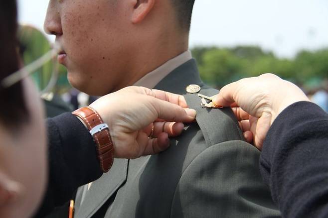 지난 5월 12일 경북 포항 해병대 교육훈련단에서 열린 해병대 부사관 400기 임관식에서 한 후보생 부모가 아들에게 하사 계급장을 달아주고 있다. ⓒ뉴시스