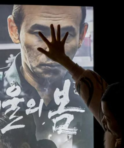 Visitors cover the face of actor Jeon Doo-kwang, who plays the film\'s protagonist, with their hands as they take a commemorative photo at a movie theater in Seoul on Nov. 11, after the film \