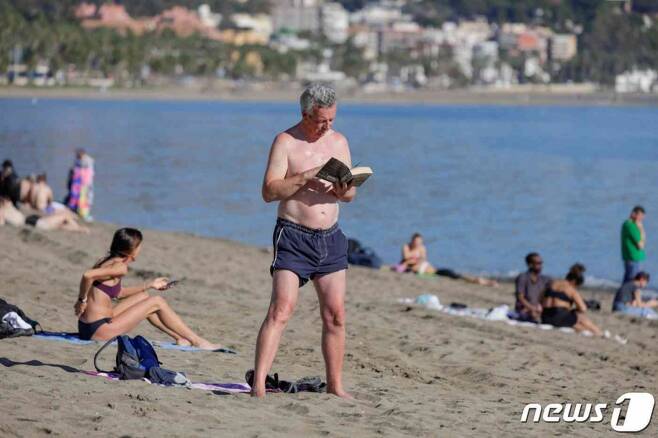 스페인 남부 도시 말라가에서 12월에도 30도에 육박하는 더운 날씨가 계속되자 한 관광객이 해변가에서 수영복만 입은 차림으로 책을 읽고 있다. /로이터=뉴스1