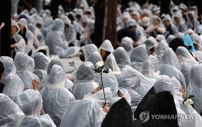 손에 쥔 추모의 꽃 학부모 악성 민원에 시달리다 극단적 선택으로 숨진 교사 A씨의 추모제가 지난 9월 15일 오후 대전시 서구 둔산동 대전시교육청 앞에서 열리고 있다. [연합뉴스 자료사진]