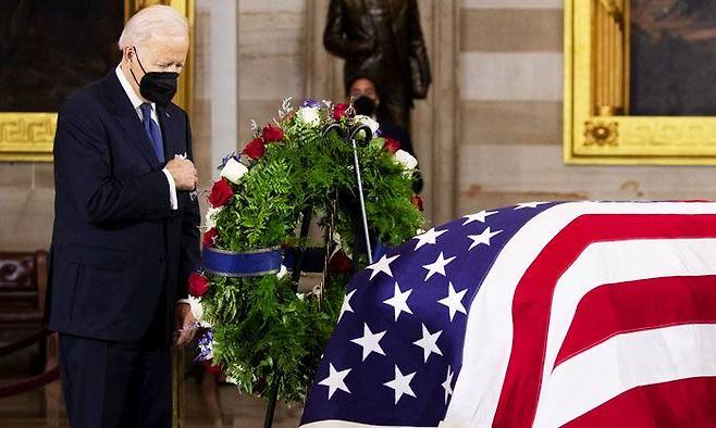 조 바이든 미국 대통령이 12일(현지 시각) 워싱턴DC 연방의회 의사당에 안치된 해리 리드 전 상원의원의 장례식에 참석해 성조기로 덮인 관 앞에서 고인을 추모하고 있다. 바이든 대통령의 지지율이 새해 들어서도 하락세를 이어가는 가운데, 일각에서는 20%대로 추락할 수 있다는 전망도 나오고 있다. /EPA 연합뉴스