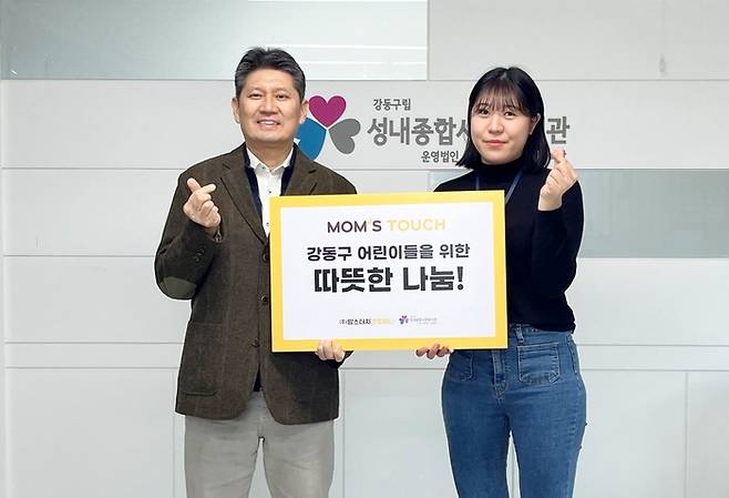 이상현 성내종합사회복지관장(왼쪽)과 이다은 성내종합사회복지관 팀장이 맘스터치 상품권 전달받고 기념사진을 찍고 있다.