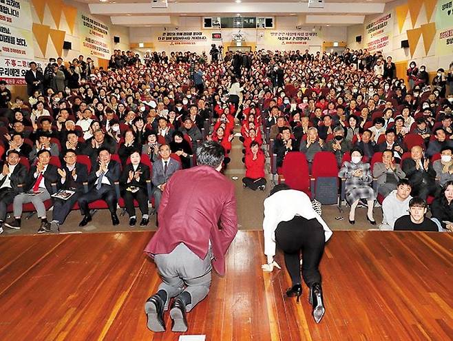 불출마 장제원 "저는 긴 터널에 들어가지만…" - 국민의힘 장제원(단상 위 왼쪽) 의원이 아내 한윤순씨와 함께 15일 부산 사상구청 강당에서 지지자들에게 큰절을 하고 있다. 내년 총선 불출마를 선언한 장 의원은 이날 의정 보고회에서 “새로운 국회가 만들어지면 저는 긴 터널에 들어간다”면서도 “내년 국민의힘이 승리해서 윤석열 대통령이 3년 반 뒤에 성공한 대통령으로 박수를 받고 나온다면 저는 그 깜깜한 터널에서 못 나와도 여한이 없다”고 말했다. /김동환 기자