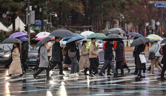 겨울비가 내리는 15일 오전 서울 광화문네거리에서 우산을 쓴 시민들이 발걸음을 재촉하고 있다. [뉴스1]