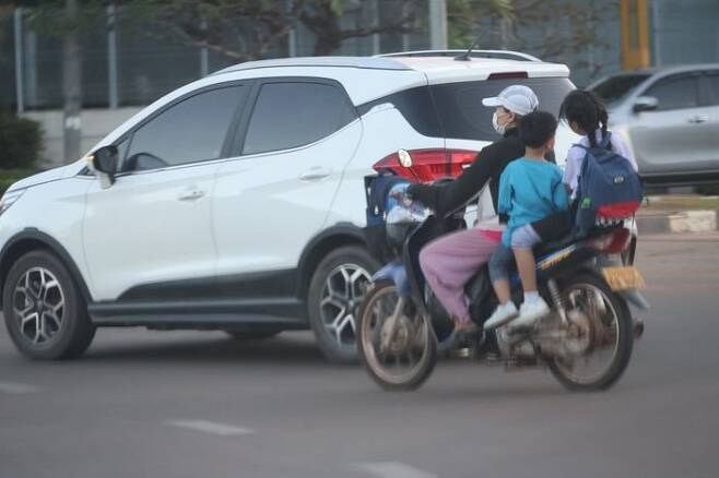오토바이에 3명이 타고 도로를 달리는 모습ⓒ