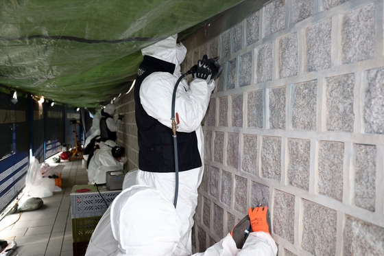 Cultural Heritage Administration officials working on the restoration of the walls of Gyeongbok Palace that were vandalized over the weekend. [YONHAP]