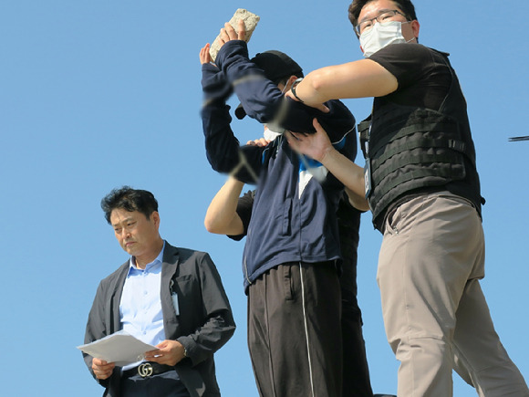 지난 7월 19일 오후 인천 중구 덕교동 잠진도 제방에서 아내를 바다에 빠트리고 돌을 던져 살해한 30대 남성이 사건 당시 상황을 재현하고 있다. [사진=뉴시스]