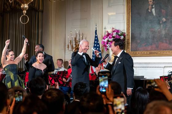 U.S. President Joe Biden, center, and Broadway stars, left, react as Korean President Yoon Suk Yeol, right, sings ″American Pie″ by Don McLean during a state dinner at the White House in Washington on April 26. [JOINT PRESS CORPS]