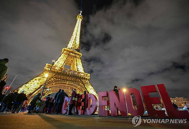 파리 에펠탑의 성탄절  (파리 AFP=연합뉴스) 프랑스 파리를 상징하는 에펠탑의 조명이 밝혀진 앞에 설치된 크리스마스라는 의미의 프랑스어 '노엘'(NOEL) 조형물을 23일(현지시간) 시민들이 둘러보고 있다. 2023.12.25