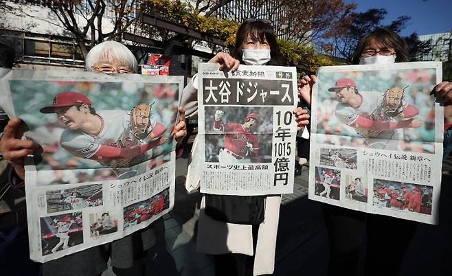 일본 시민들이 오타니 쇼헤이의 LA 다저스 계약 호외 신문을 들고 있는 모습. AFP=연합뉴스