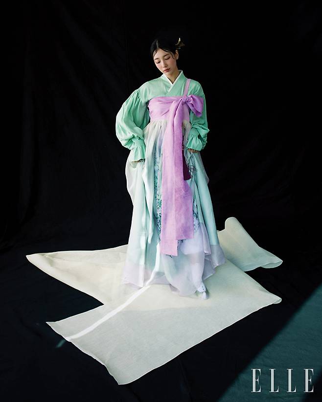 김환기 화백의 회화 색감과 수지를 연상케 하는 등꽃에서 영감을 받아 한복의 아름다움을 표현한 차이 킴. 고려청자의 은은한 색감과 항아리 느낌의 실루엣으로 흐르듯 디자인했으며, 16세기 거들 치마를 차이 킴 스타일로 재해석한 것이 특징이다.