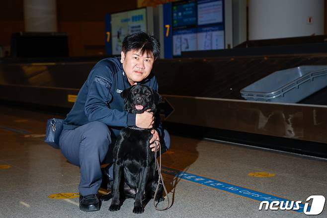 탐지견 에이스(5·래브라도 리트리버)가 탐지조사요원인 박지용 주무관(50)과 인천국제공항 제2터미널 입국장에서 여행객들의 수화물을 검색한 뒤 포즈를 취하고 있다. ⓒ News1 안은나 기자