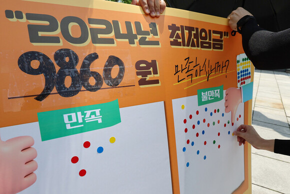 지난 7월 19일 오후 서울 종로구 마로니에공원에서 한 시민이 내년도 최저임금에 관한 의견을 묻는 스티커 설문에 참여하고 있다. 연합뉴스