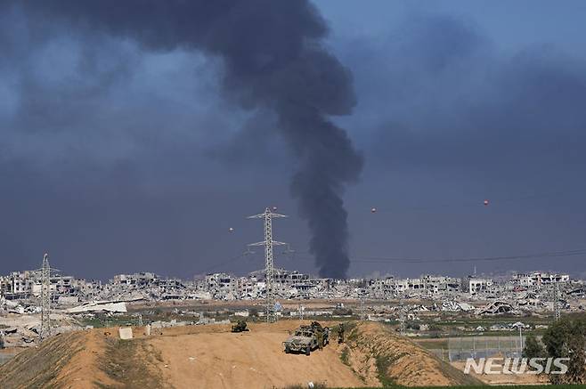 [가자지구=AP/뉴시스] 29일(이스라엘) 이스라엘의 공습으로 가자지구에서 연기가 피어오르는 가운데 이스라엘 군인들이 이스라엘 남부 가자지구 인근에 진을 치고 있다. 2023.12.29.