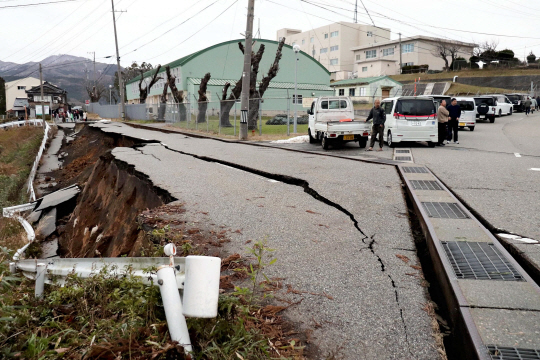 1일 오후 강진이 발생한 일본 이시카와현 와지마에서 대규모 균열이 발생한 도로 옆에 서 있다. AFP 연합뉴스