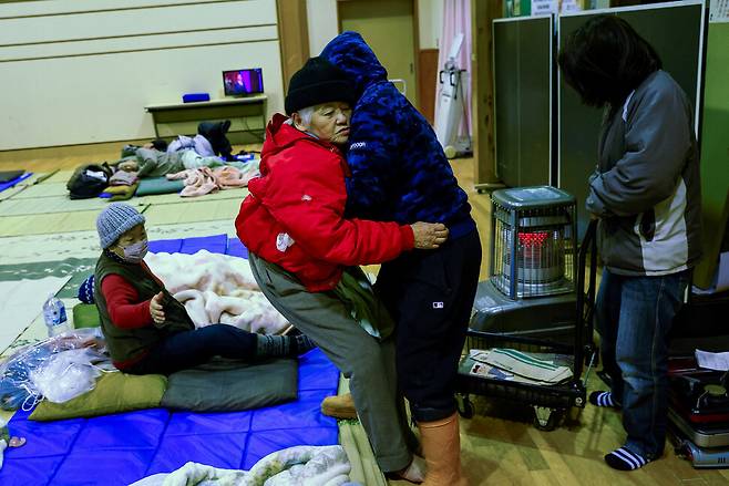 2일 일본 이시카와현 와지마에서 한 남성이 지진 여파로 대피소로 개조된 커뮤니티 센터에서 어머니를 매트리스에 눕히고 있다. 로이터 연합뉴스