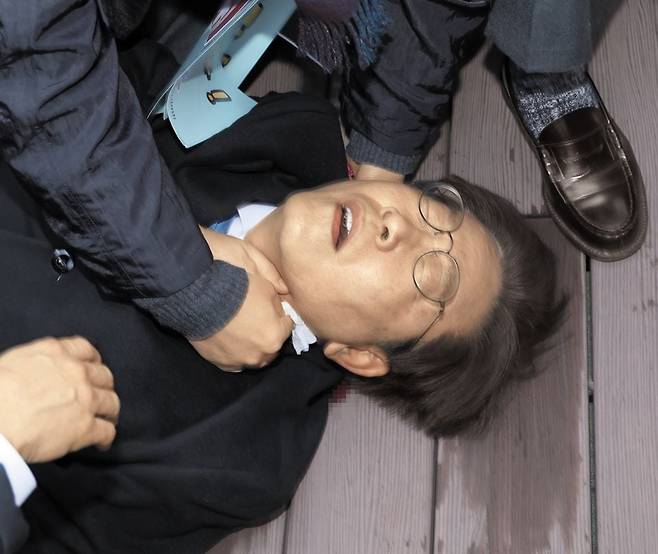 더불어민주당 이재명 대표가 2일 부산 가덕도 신공항 부지 방문을 마친 뒤 이동하던 순간에 괴한의 흉기 습격을 당해 바닥에 쓰러져 있다. 이 대표는 목 부위가 1.5cm 정도 찢어졌고 경정맥에 손상을 입은 것으로 알려졌다. 이 대표는 부산대병원으로 옮겨진 뒤 이후 헬기로 서울대병원으로 이동해 수술을 받았다. /뉴시스