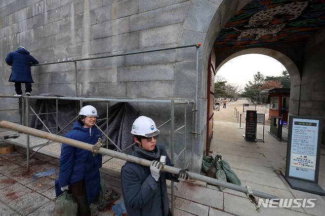 [서울=뉴시스] 조성우 기자 = 문화재청 관계자들이 4일 오전 낙서 복구 작업을 위해 설치됐던 서울 종로구 경복궁 영추문 담벼락 가림막 제거 작업을 하고 있다. 2024.01.04. xconfind@newsis.com