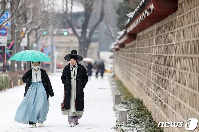 서울을 비롯한 전국에 대설주의보가 발효된 9일 서울 종로구 경복궁 건춘문 앞에서 한복차림 위에 두꺼운 겨울외투를 껴입은 대만인 관광객들이 눈을 맞으며 걸음을 옮기고 있다. 2024.1.9/뉴스1 ⓒ News1 민경석 기자