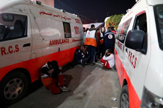 가자지구 중부 데이르알발라에서 10일 의료진이 구급차 주변에 모여 이스라엘군 공격으로 숨진 동료들을 애도하고 있다. 데이르알발라=로이터 연합뉴스