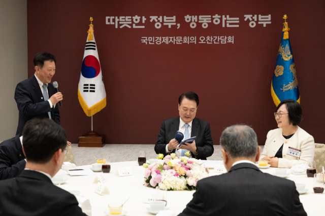 윤석열 대통령이 11일 서울 용산 대통령실 청사에서 열린 국민경제자문회의 위원들과의 오찬 간담회에 참석해 자문회의가 발간한 연례 보고서를 살펴보고 있다. 사진 제공=대통령실