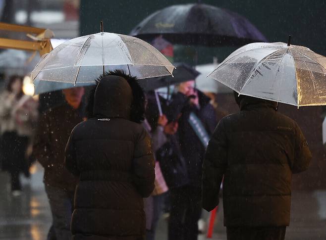 지난해 12월6일 비가 내린 서울 중구 롯데백화점 본점 앞으로 패딩을 입은 시민들이 우산을 쓰고 걷고 있다. 연합뉴스