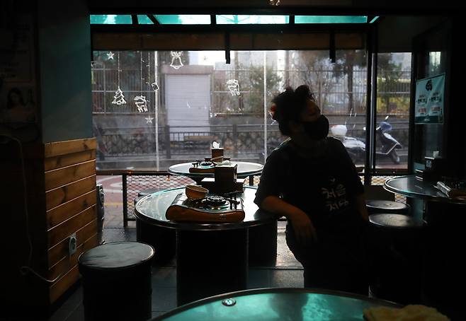 한 식당 업주가 썰렁한 식당 안에서 뉴스를 보며 앉아 있다. 연합뉴스