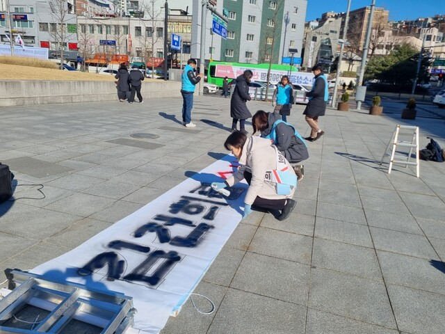 15일 진보당 서대문구위원회 관계자들이 현수막에 락커로 ‘김건희 수사하라’를 작성하는 퍼포먼스를 하고 있다. 고나린 기자