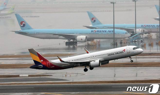 인천국제공항 계류장에 세워진 대한항공 항공기 앞으로 아시아나 항공기가 이륙하고 있다./사진=뉴스1